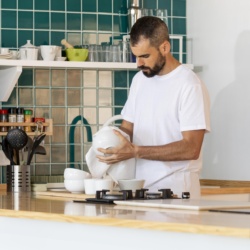 Homme essuyant de la vaisselle dans une cuisine.